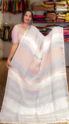 Woman holding a white saree with horizontal stripes in a clothing store.