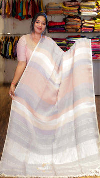 Woman holding a white saree with horizontal stripes in a clothing store.