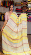 Woman holding a yellow and pink striped saree in a clothing store.