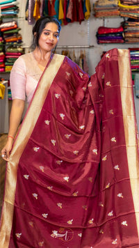 Woman wearing a maroon saree with gold patterns in a store setting