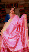 Woman wearing a pink saree with a blue blouse in a fabric store.