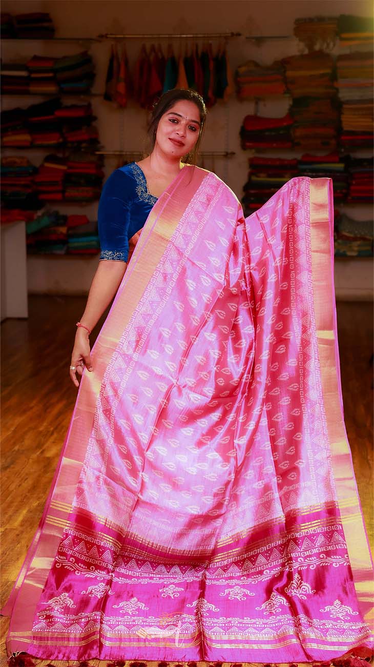 Woman wearing a pink saree with a blue blouse in a fabric store.