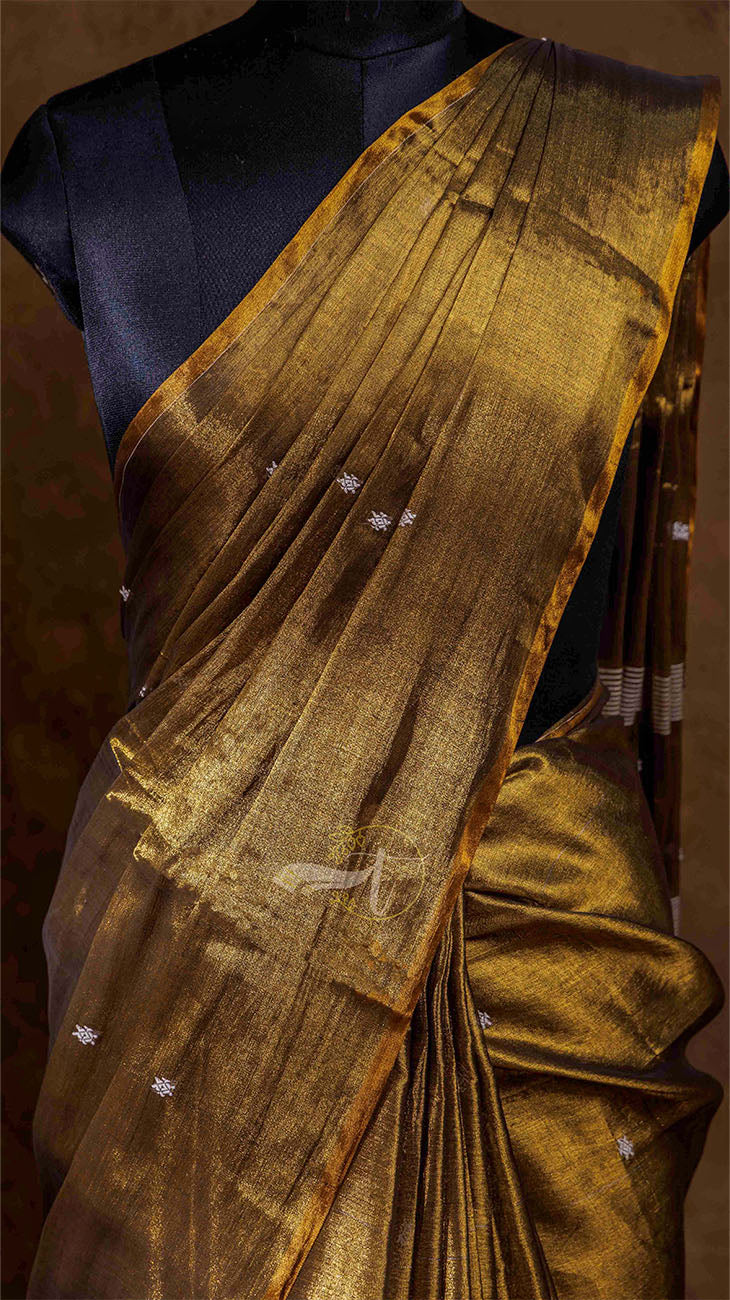 Gold saree with a black blouse on a mannequin against a dark background